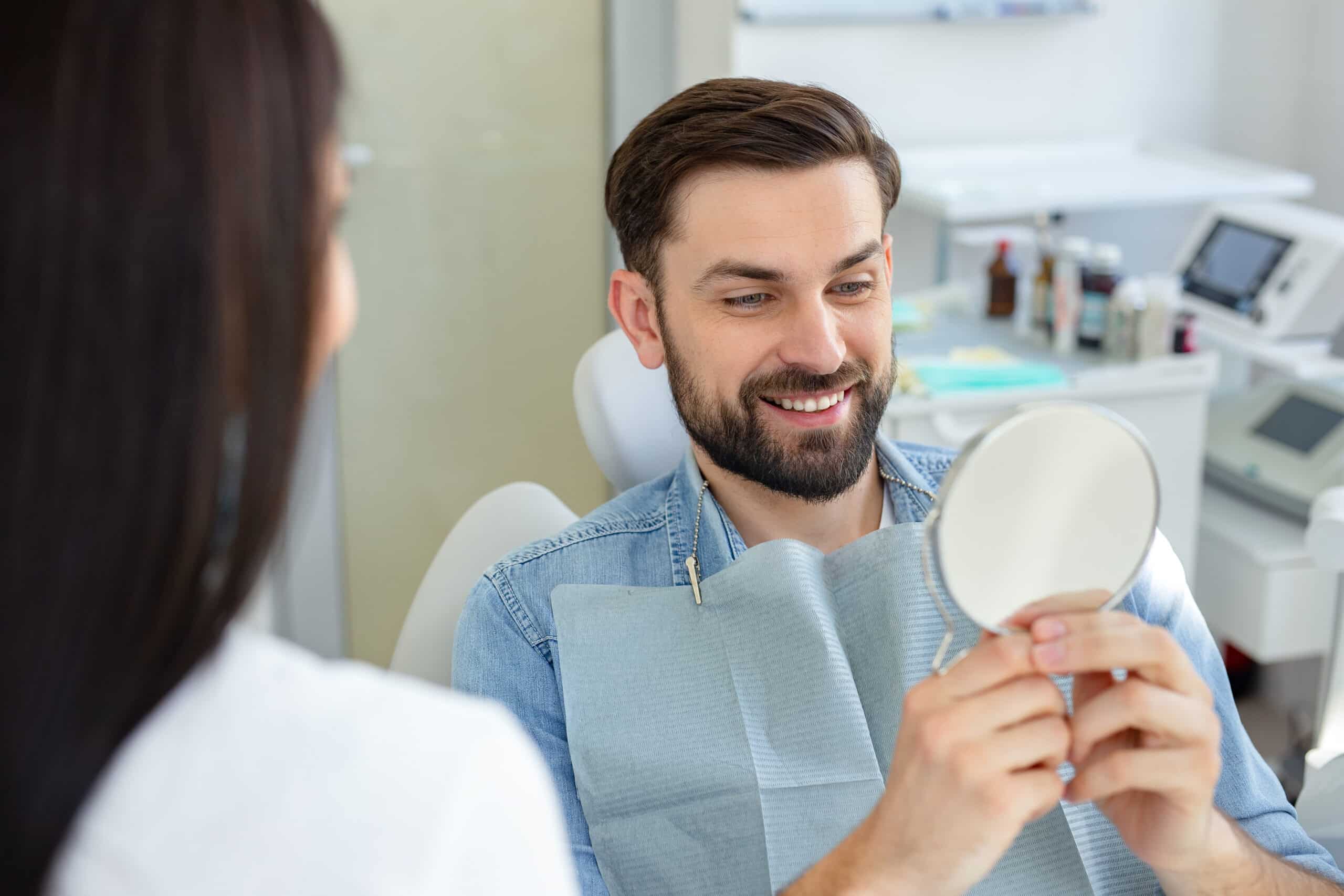 Portrait,Of,Smiling,Client,Looking,At,Teeth,In,The,Mirror